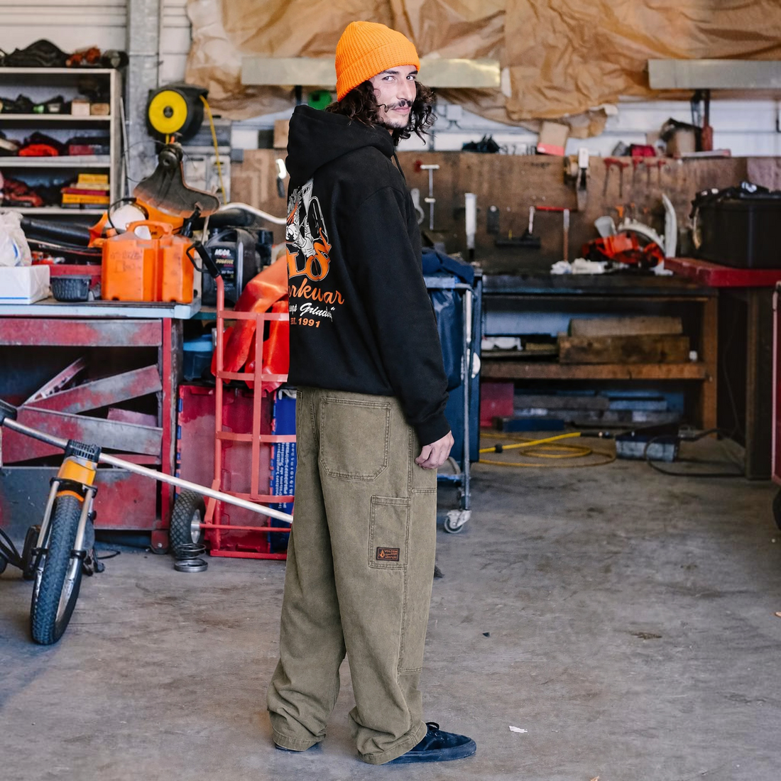 Homme portant le pantalon carpenter Born2ride Volcom couleur terre en coton épais dans un atelier