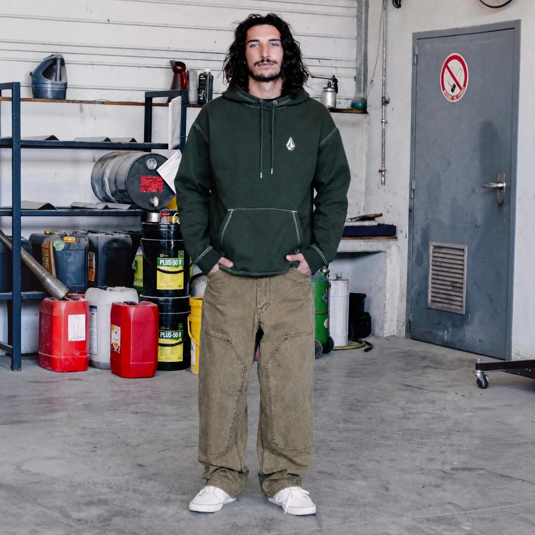 Homme portant le pantalon Born2ride Volcom Work Carpenter couleur Earth en coton épais dans un atelier