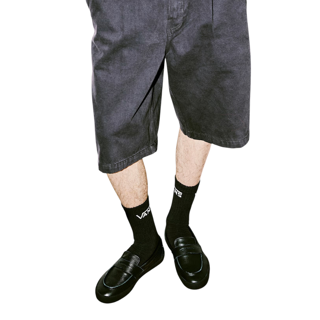 Homme portant des chaussures Vans Skate Loafer noires avec des chaussettes Vans et un short, style streetwear