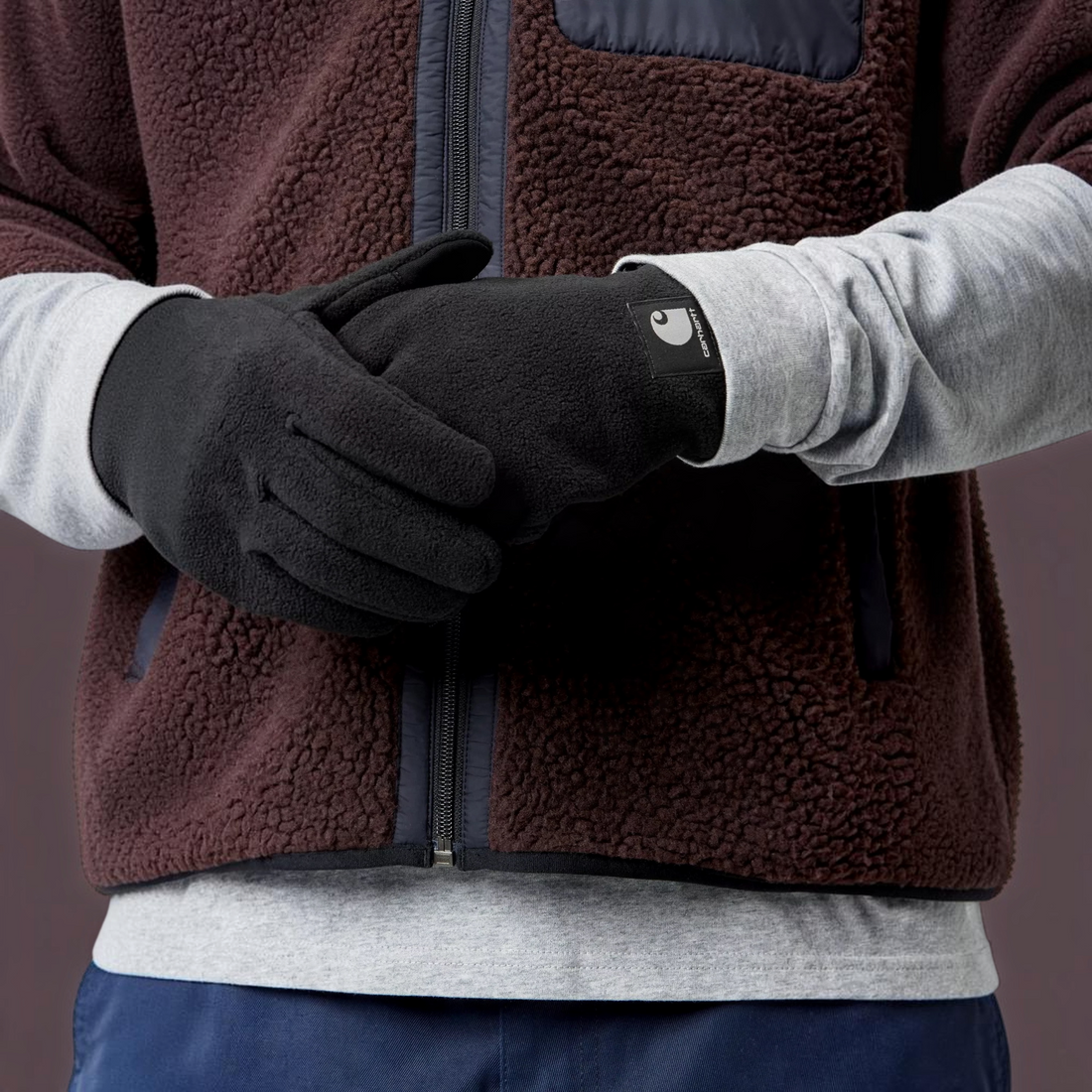 Gants en polaire noire Carhartt WIP Blevin avec étiquette logo et doigts tactiles portés par un modèle