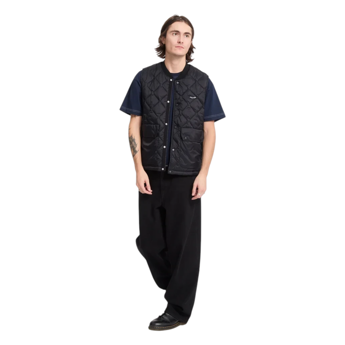 Homme portant un gilet matelassé noir Volcom Bowered de Born2ride avec un t-shirt bleu marine et un pantalon noir