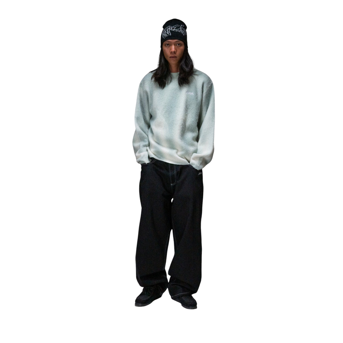 Homme portant le pull en maille Jacker Blur Knit AOP de Born2ride avec un bonnet noir et un pantalon large