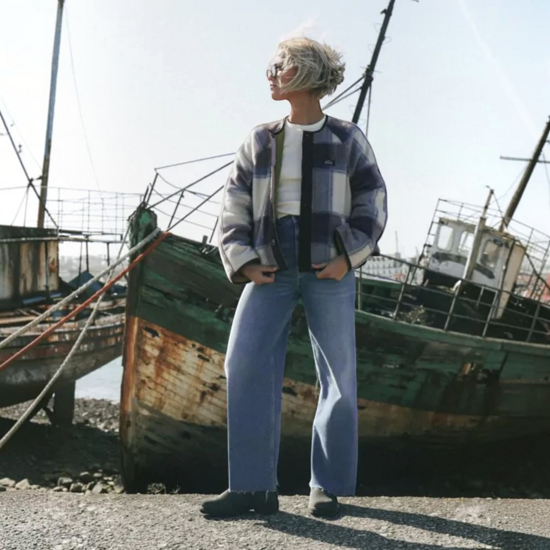 Femme portant le jean Born2ride Oxbow Mariner-pt bleu vintage indigo, coupe droite stretch, devant un vieux bateau