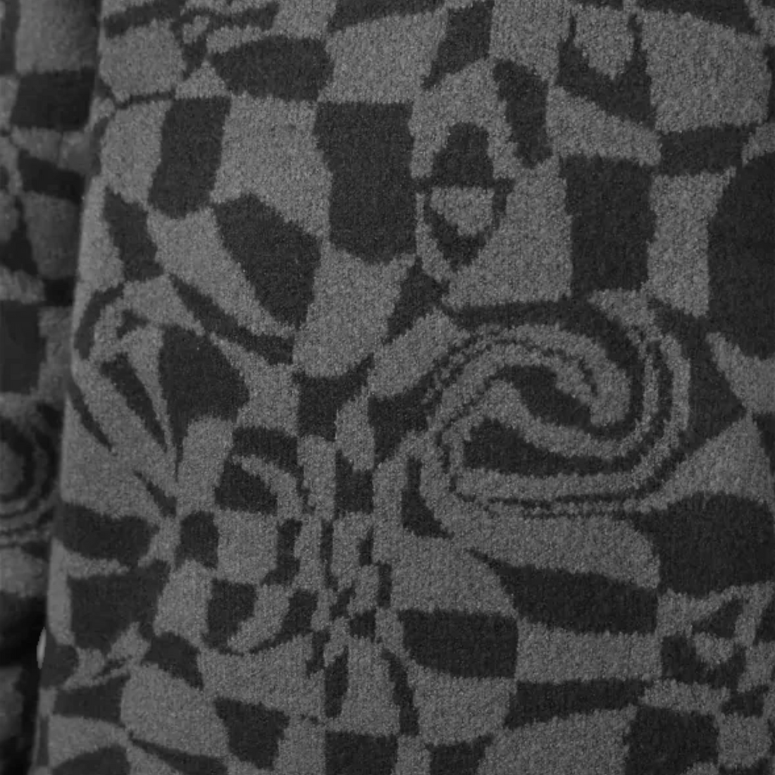Gros plan sur le tricot souple noir et gris du pull Oxbow Twist-jp vendu par Born2ride avec un motif abstrait