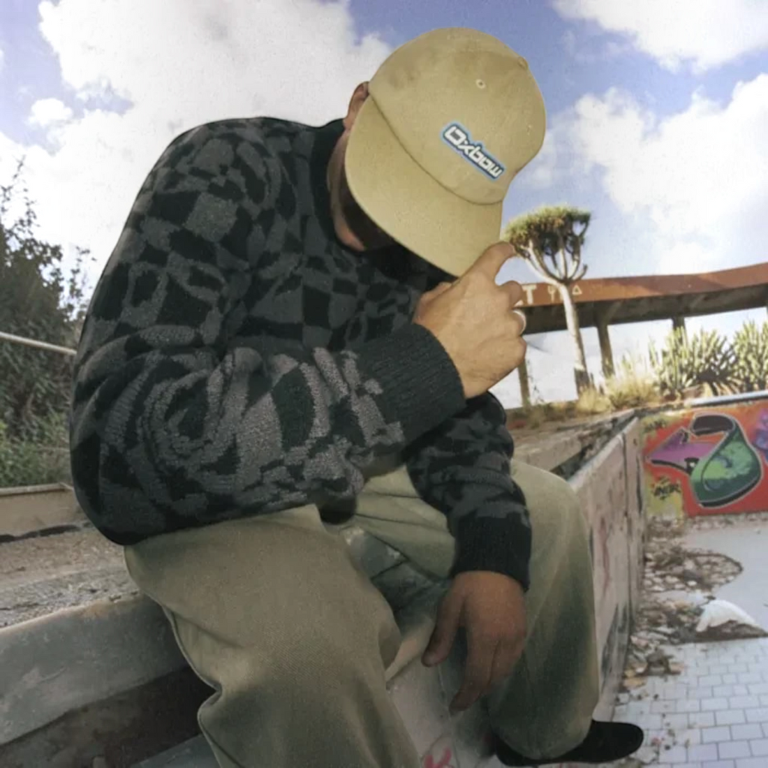 Homme portant un pull Oxbow Twist-jp noir à motifs géométriques et une casquette beige, style surfwear chez Born2ride