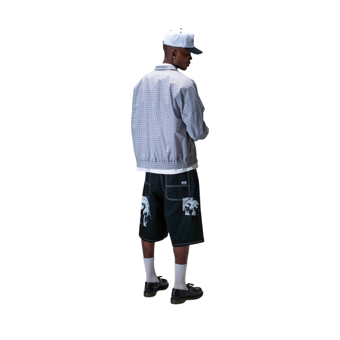 Homme portant la veste Born2ride Street Check à carreaux gris avec une casquette et un short noir imprimé