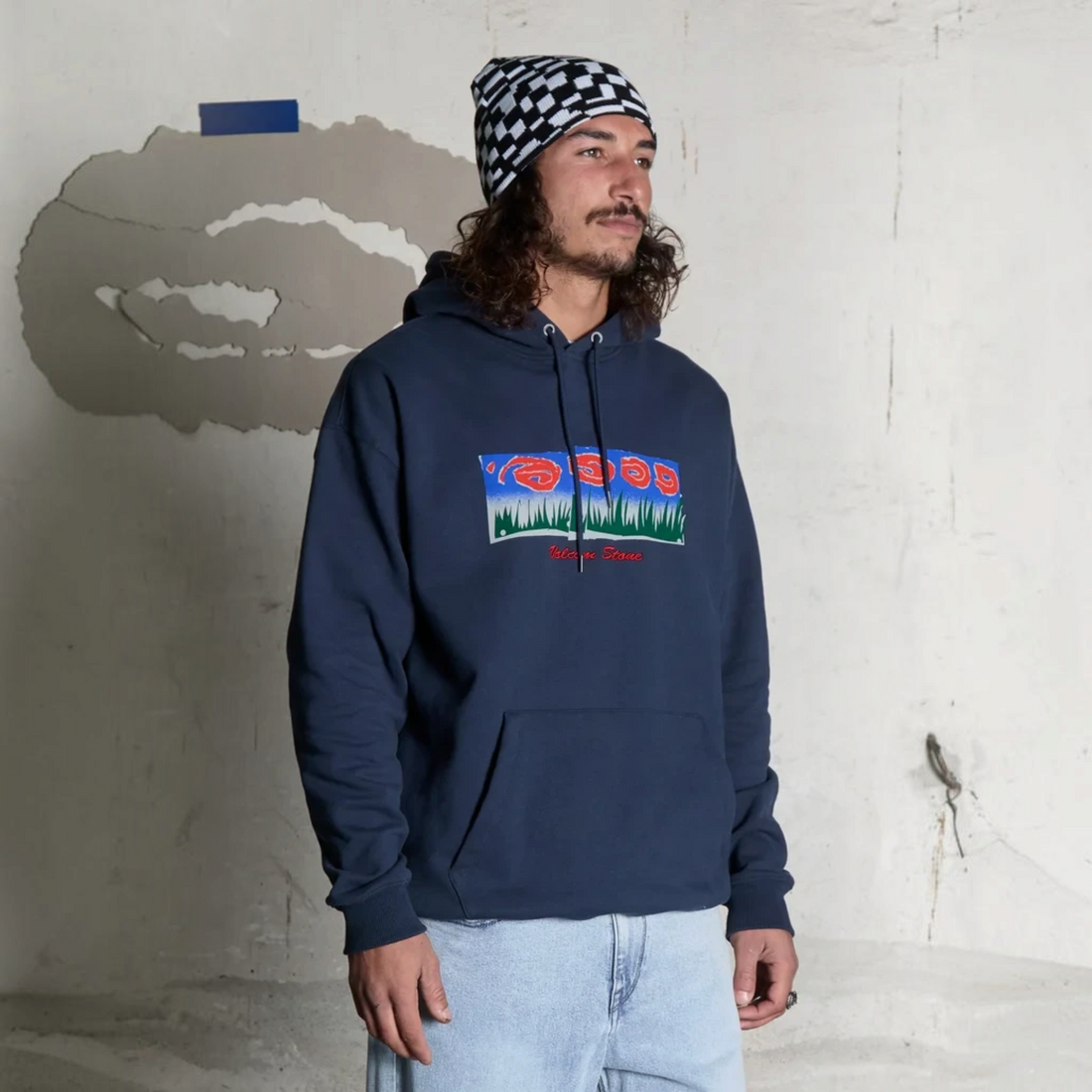 Bonnet Born2ride Volcom Fa Carrau blanc à motif damier porté par un homme avec un sweat à capuche bleu marine