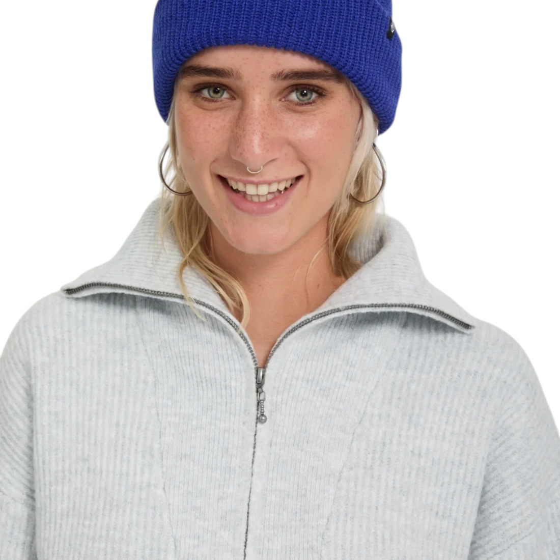 Femme souriante portant le pull Born2ride Volcom Voltrane chiné beige à col zippé et un bonnet bleu vif