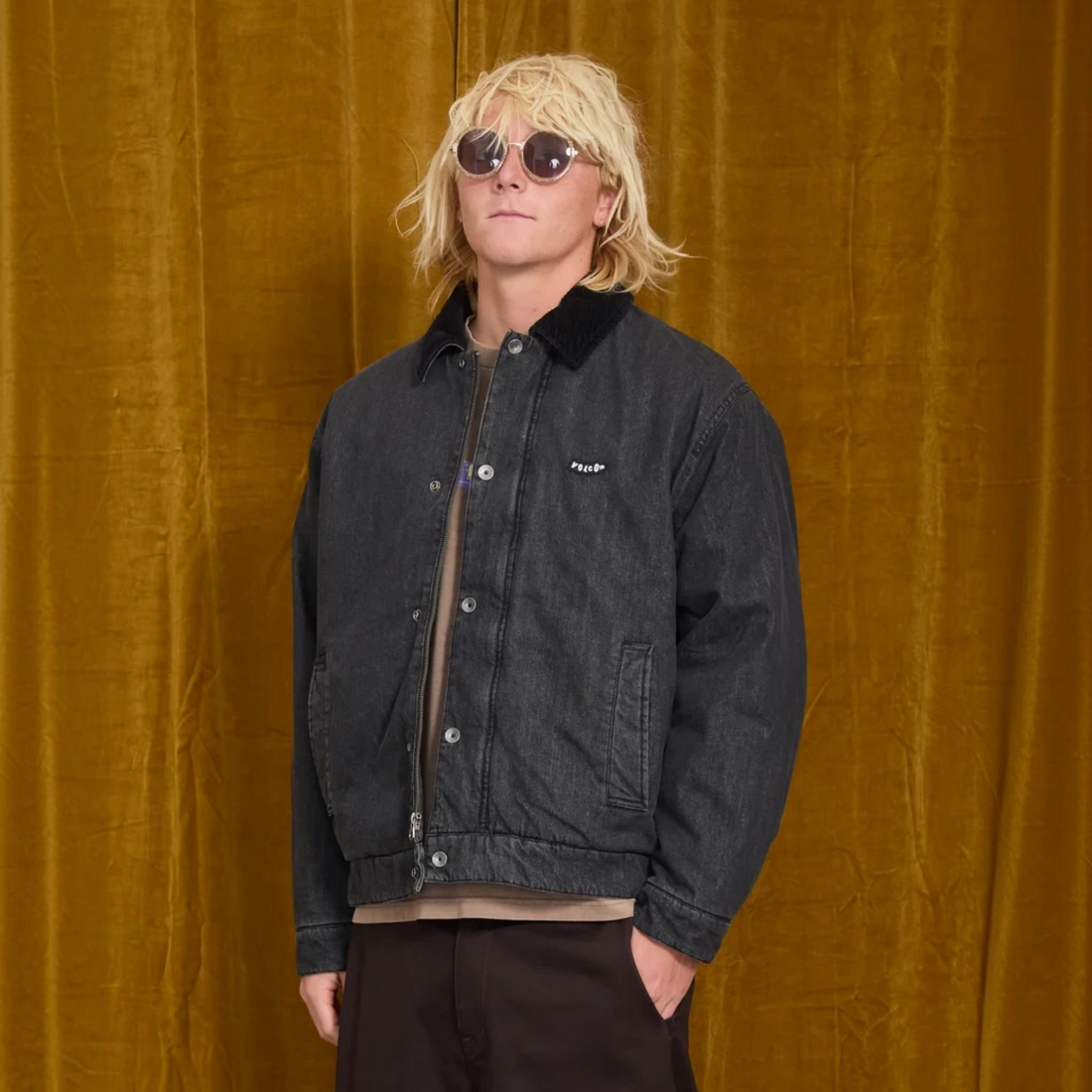 Homme portant la veste Born2ride Volcom Stonewish noire en coton avec col contrasté sur fond rideau doré